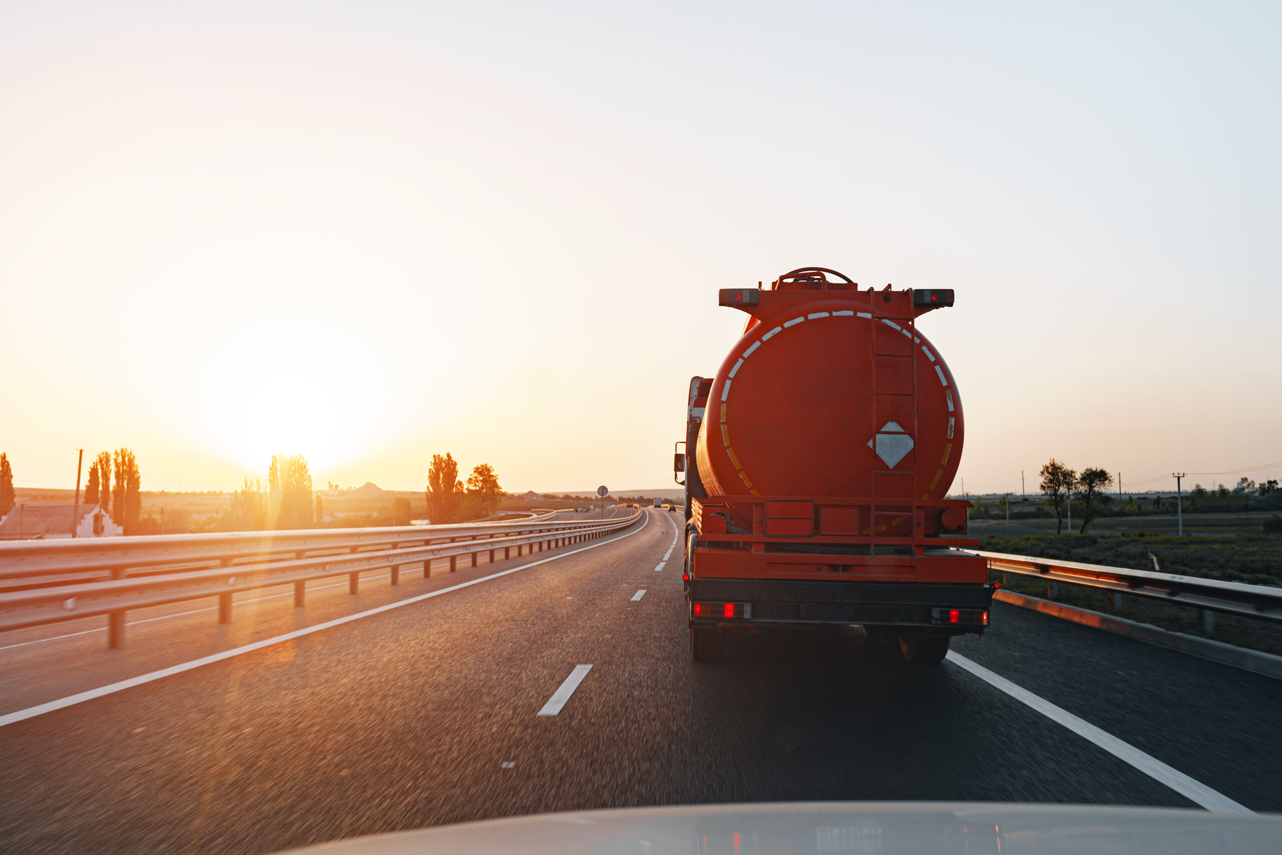Truck driving on highway road at sunrise, view from car